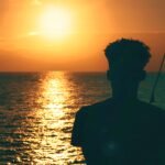 Jamaica The Caribbean & The World Needs To Go Green Photo Of Young Staring Out To Sea As The Sun Sets.