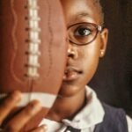 The Songs Bad Bunny Should Perform At The SuperBowl Young Black Girl Holds Up American Football.