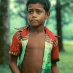 Caricom Climate Change Young Boy in rainforest with apprehensive look on his face