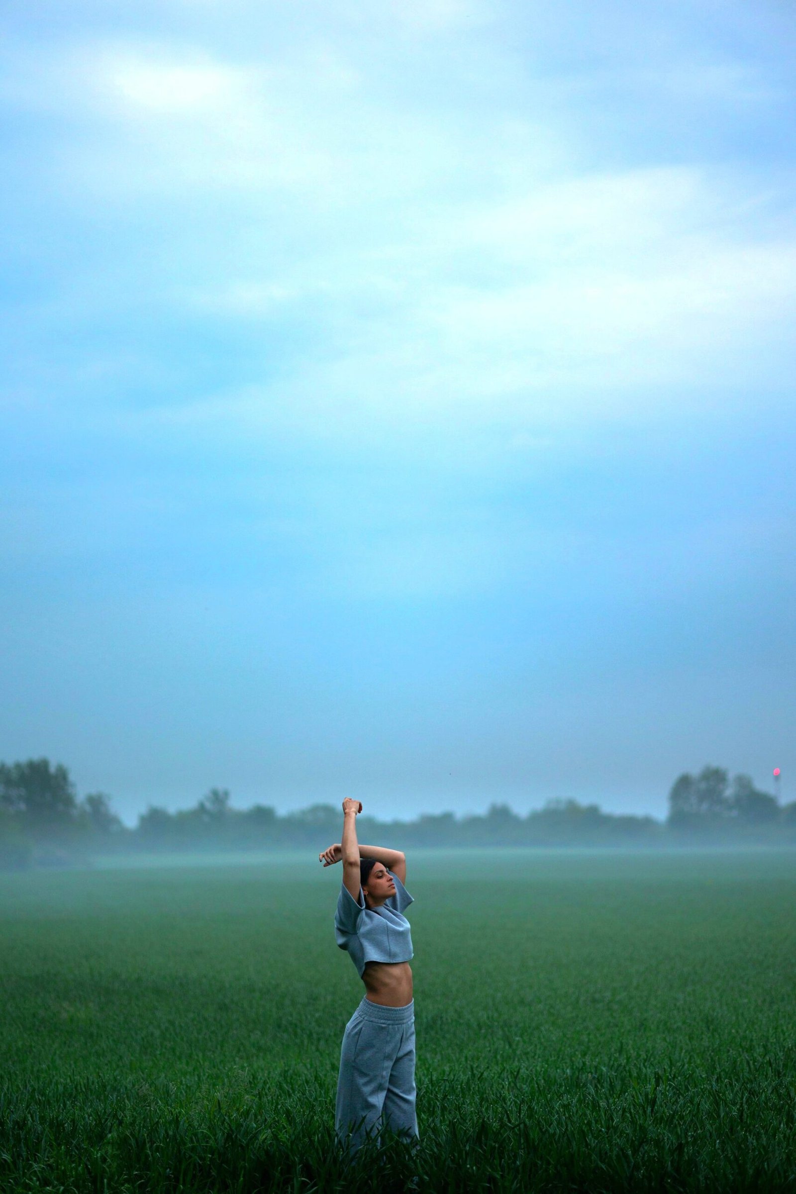 Greener. Pic Of Young Woman stretching in field of green grass